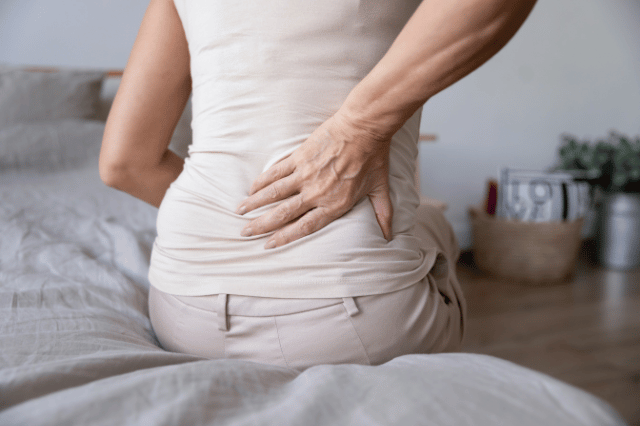 Female sitting on the bed holding her back in pain with sciatica