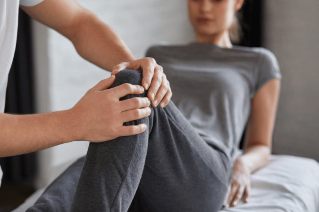 Male physiotherapist treating a female patient knee