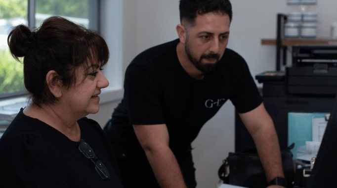Two people in an office are looking at a computer screen together.