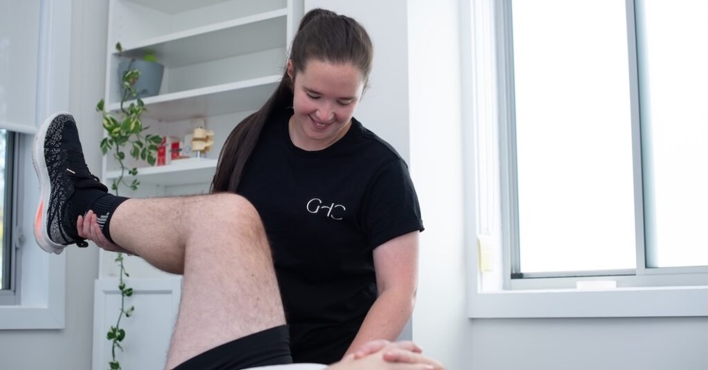 Physical therapist assists a person with a leg exercise in a bright, modern room.